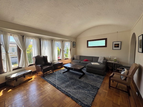 Una sala de estar con sofá, sillones, una mesa de centro, alfombra y una maleta.