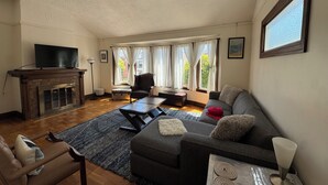 Un salon avec une cheminée, un canapé, un fauteuil et un téléviseur.