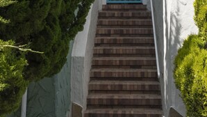 Un escalier menant à une porte portant le numéro 58, le tout entouré de verdure.