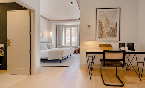 Une chambre d’hôtel moderne, équipée d’un lit, d’un bureau, d’une chaise et d’une œuvre d’art au mur.