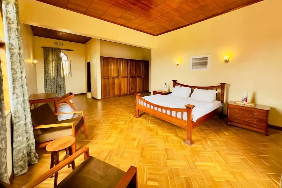 A spacious bedroom with a wooden bed, a desk, and a chair.