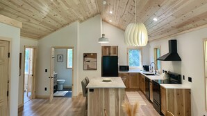 A modern kitchen with wooden cabinetry, a central island, and a black range hood. - Modern Design - Fire Pit - Lake Access (Montello)