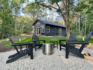 Fire pit and home with a backdrop of tall pines