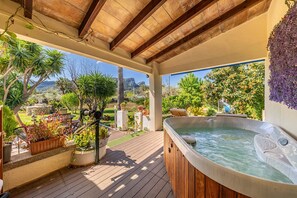 A hot tub on a wooden deck with a garden view.