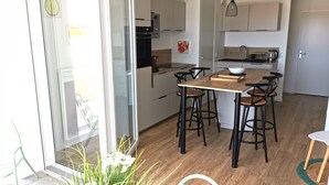 Eine moderne Küche mit einer zentralen Kochinsel, Barhocker und einer Glastür zum Außenbereich.