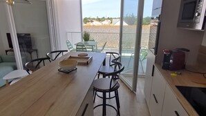 Eine moderne Küche mit Essbereich, einem großen Fenster und Blick auf die Nachbarschaft.