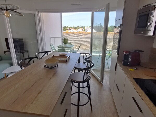 A modern kitchen with a dining area, a large window, and a view of the neighborhood.