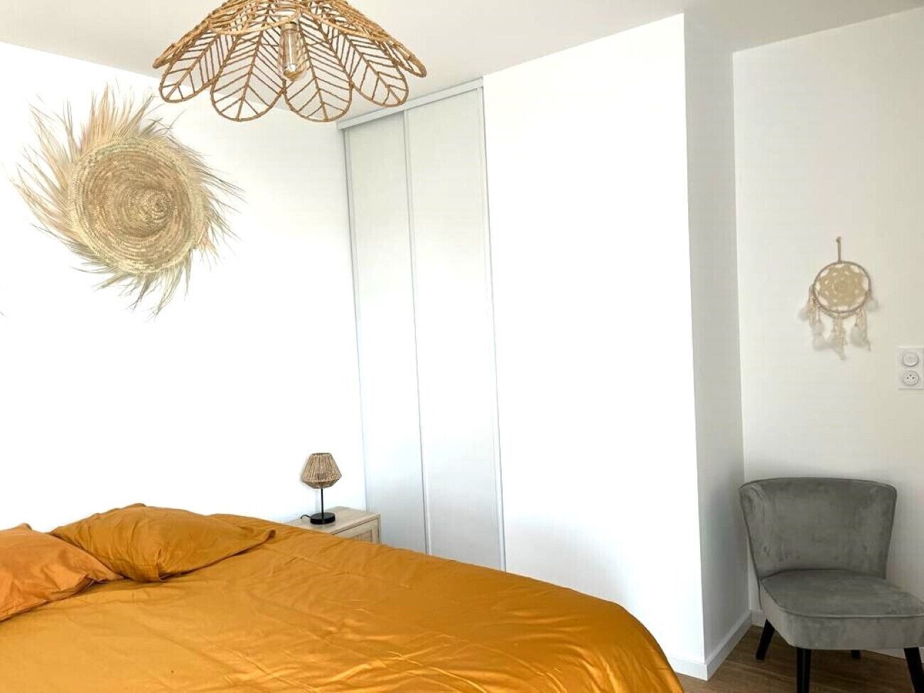 Un dormitorio con cama, mesita de noche, silla, armario y un adorno en la pared.