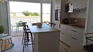 Eine moderne Küche mit Kochinsel, Barhocker und Blick auf die Terrasse.