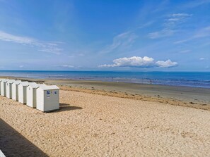 Ein Strand mit mehreren mobilen Toiletten, die in einer Reihe im Sand aufgestellt sind.