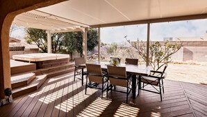 An outdoor patio with a wooden deck, a covered seating area, and a view of the surrounding landscape. - Entire Home Close To Everything (Albuquerque)