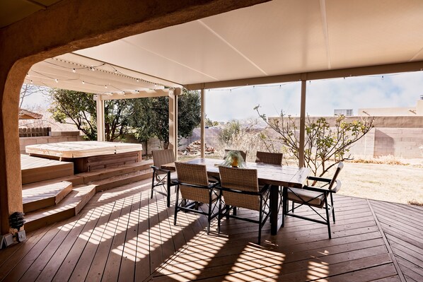 An outdoor patio with a wooden deck, a covered seating area, and a view of the surrounding landscape.