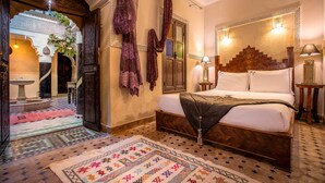 Une chambre au décor traditionnel, avec un lit, des tapis à motifs et une tête de lit décorative.