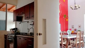 A kitchen with dark wooden cabinets, a white door, and a dining area with a red accent wall and wooden chairs.