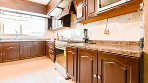 Een keuken met houten kastjes, een fornuis en een magnetron.