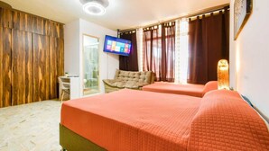 Een hotelkamer met twee bedden, een bureau, een stoel, een televisie en een raam met gordijnen.