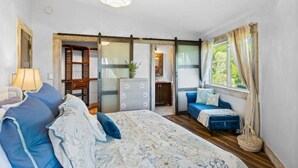 Ein Schlafzimmer mit einem großen Bett, einem Nachttisch, einer Kommode und einem Fenster mit Vorhängen.