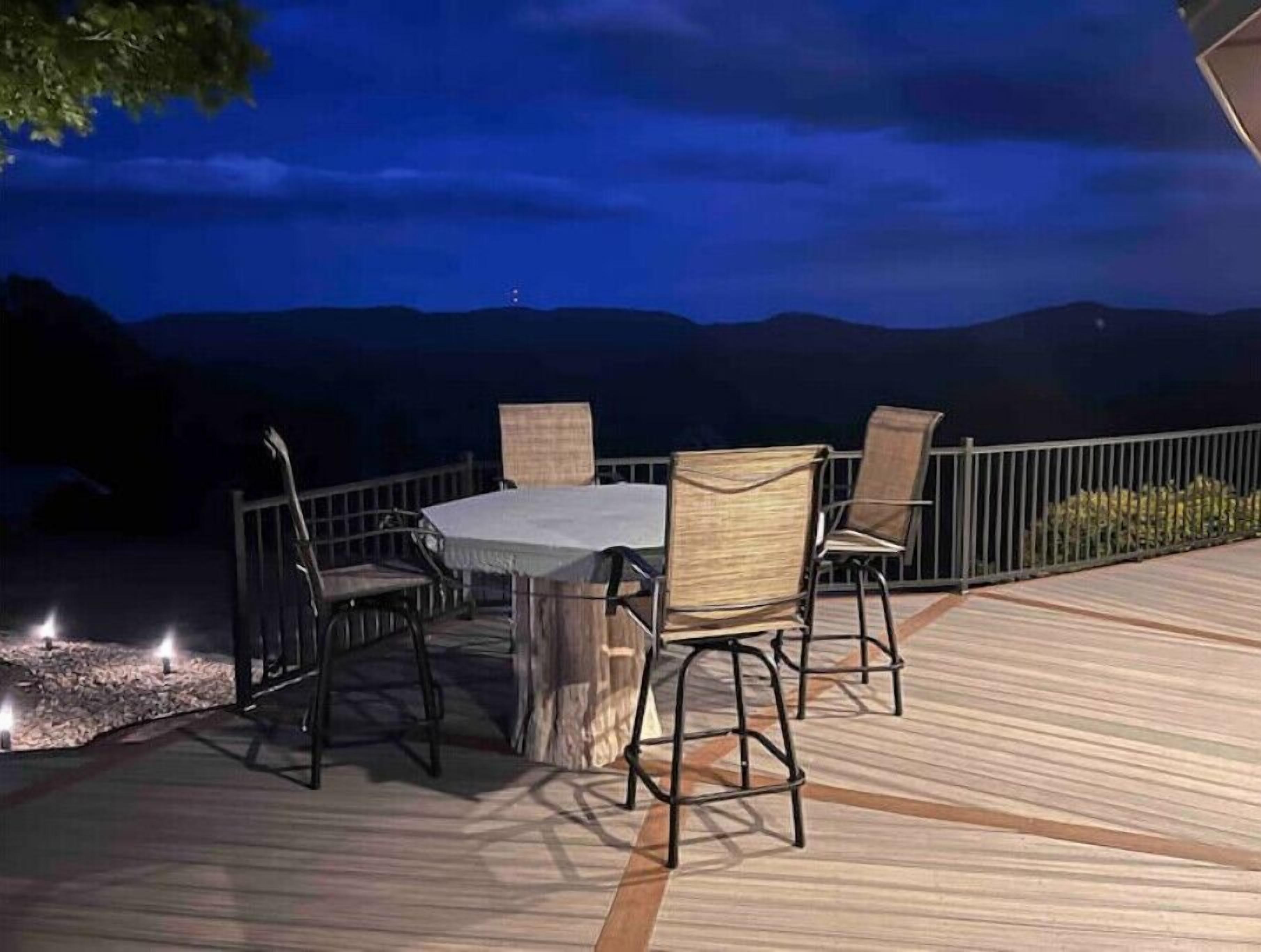 Een buitenplaats met eettafel en stoelen, omgeven door een houten terras en een metalen hekwerk.