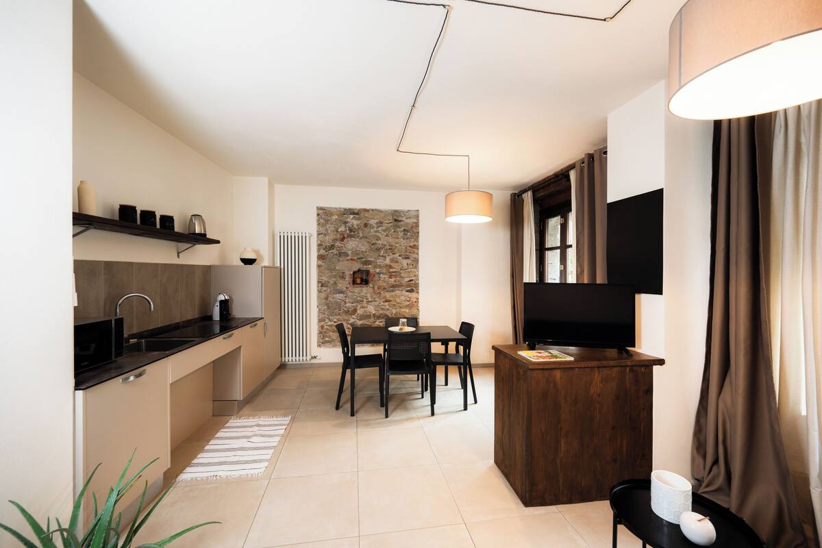 Una cocina compacta con comedor, pared de piedra decorativa y televisor montado en la pared.