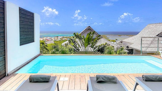 A modern pool area with lounge chairs and a view of the ocean.