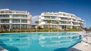 Ein modernes Hotel mit Pool, das gewölbte Balkone und ein klares, blaues Wasser bietet.