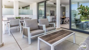 Ein moderner Außenbereich zum Sitzen mit weißer Möbel und einem Holztisch.