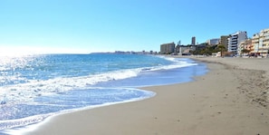 A beach with a clear sky, waves, and buildings in the background. - ViVi Homes pool, Cameron apartment (Fuengirola)