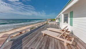 A wooden deck with lounge chairs, a white building with green shutters, and a beach view. - Elbow Reef (Hope Town)
