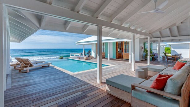 A covered outdoor area with a pool, wooden deck, and seating. - Elbow Reef (Hope Town)