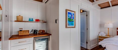 Una habitación pequeña con kitchenette, una cama y una puerta que da a otra habitación.