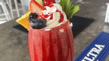 A cocktail with fruit garnish on a bar mat labeled "ULTRA" in a bar setting.