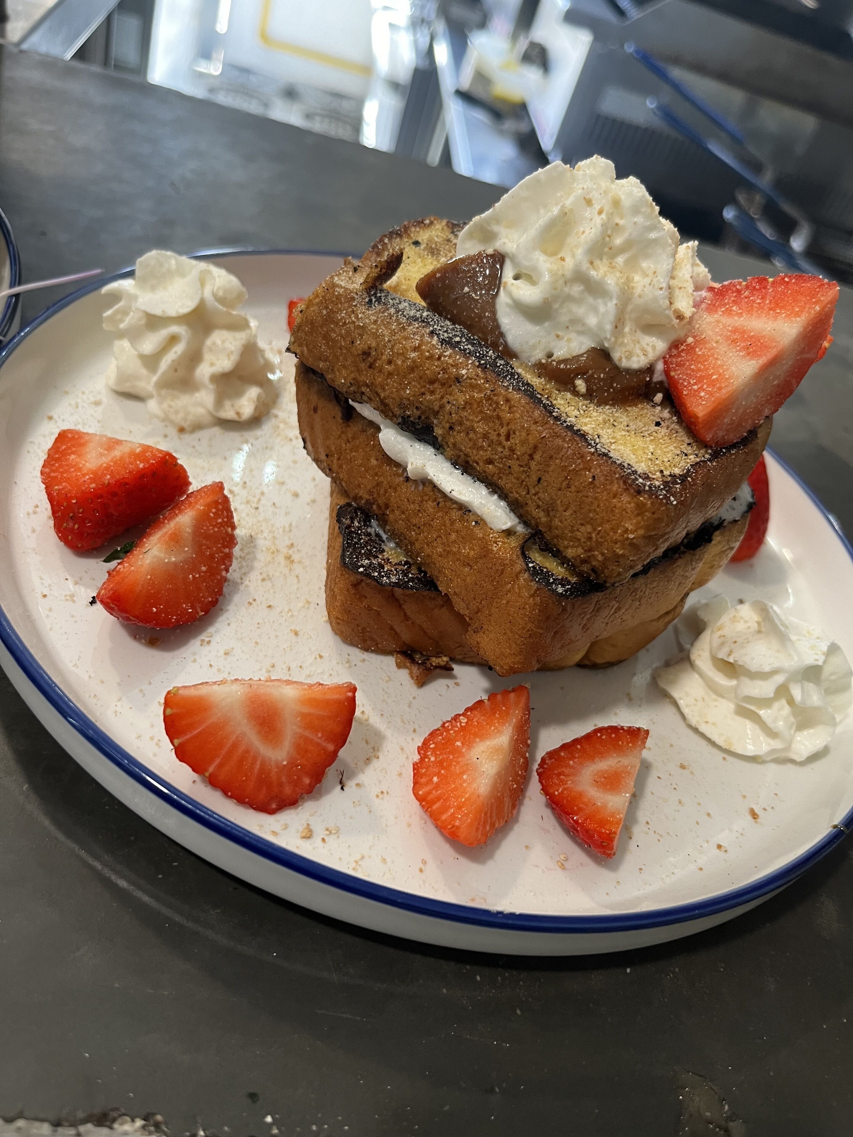 A plate with a layered dessert, strawberries, and whipped cream.