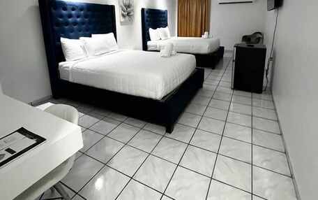 A modern hotel room with two beds, a desk, and a flat-screen TV.