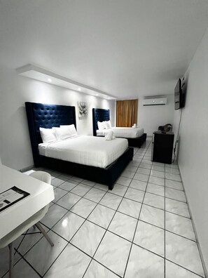 A modern hotel room with two beds, a desk, and a flat-screen TV. - Douglas Highway Hotel (Cabo Rojo)