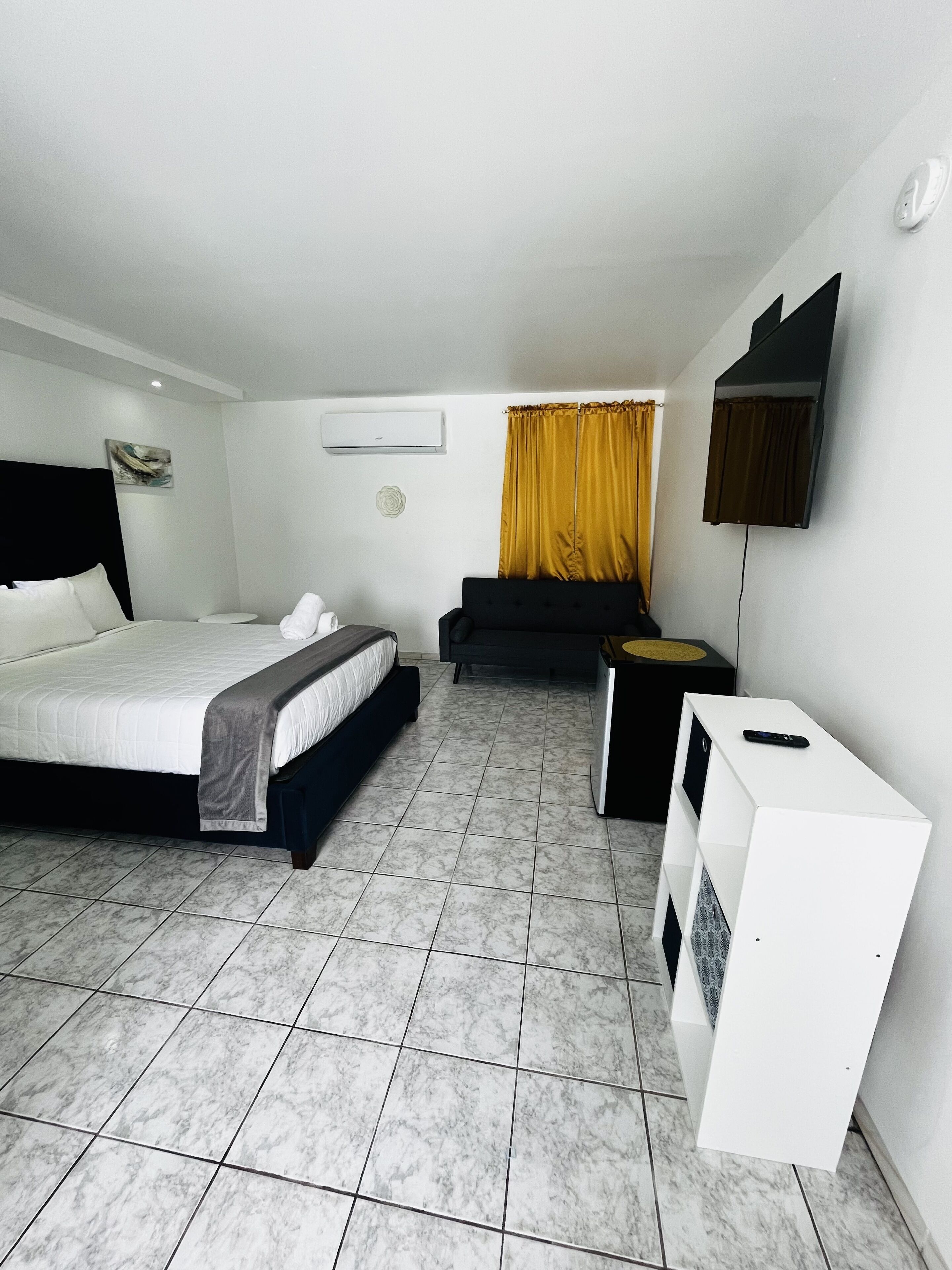 Una habitación de hotel con cama, sofá, televisor y una mesita.