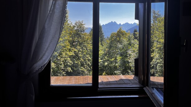 A room with a large window overlooking a mountainous landscape. - Hotel Bosco Verde (Val di Zoldo)
