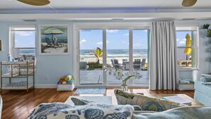 Un salon spacieux doté d’une grande porte-fenêtre coulissante donnant sur un balcon avec vue sur la plage.