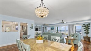 Amplia sala de estar con una mesa de comedor, paredes de tonos claros y vista al océano.