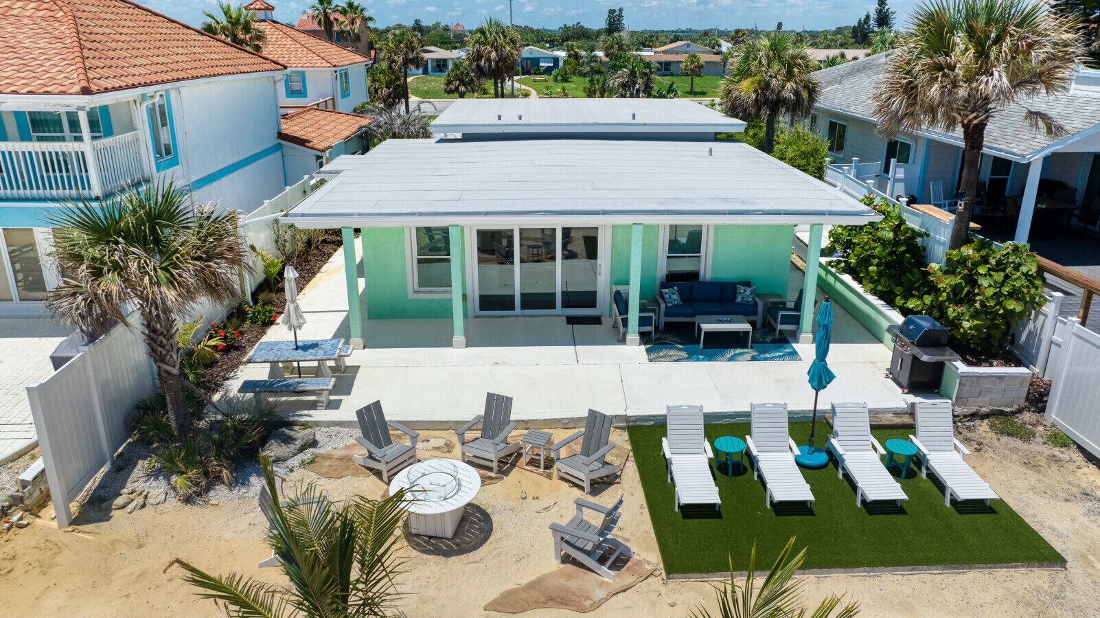 Une maison dotée d’un patio aménagé avec du mobilier d’extérieur et un barbecue.