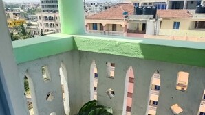Ein Balkon mit grüner Geländer, Blumentopf und Blick auf benachbarte Gebäude.
