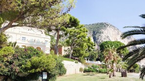 A building with a balcony, surrounded by trees and a mountain backdrop.