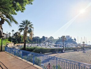 A marina with boats, a sandy beach, and a blue fence.