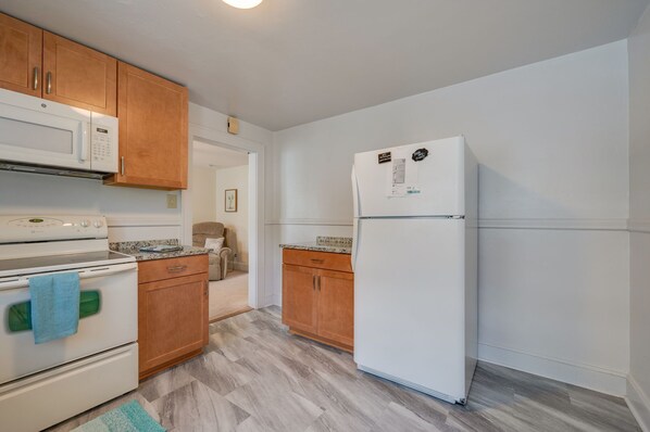 A compact kitchen with wooden cabinets, a white refrigerator, and a stove. - Olde Hampton, right in the center of Hampton Roads 2 (Hampton)