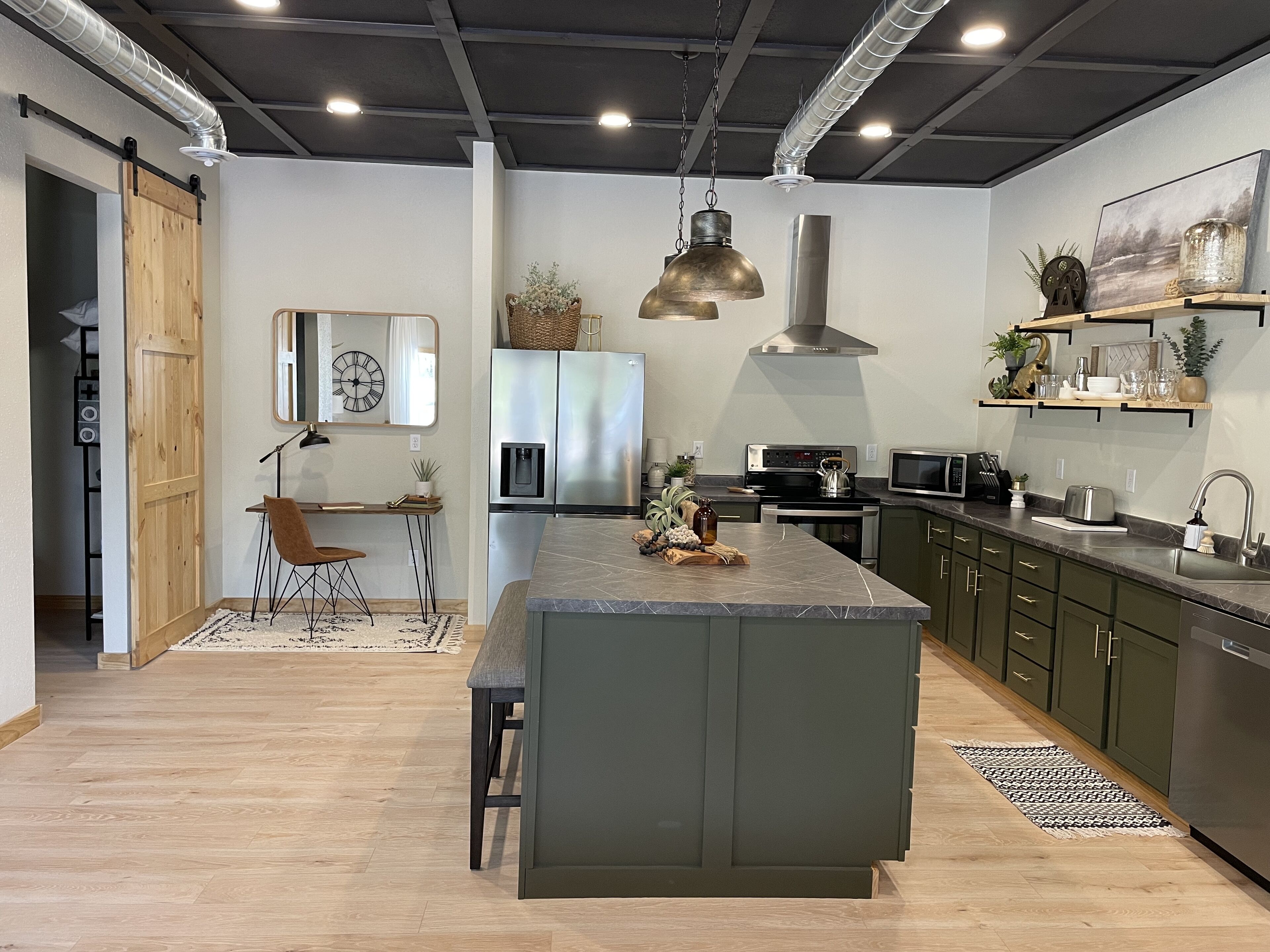 Een moderne keuken met een centraal eiland, roestvrijstalen apparatuur en een eethoek met een houten tafel en stoelen.