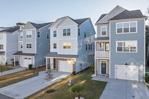 A row of townhouses with attached garages, a small front yard, and a clear driveway. - 4 Luxury Home w/ Pool, FirePit, Outdoor Dining,| The Marshes Broad View (Hilton Head Island)