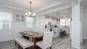 A spacious dining area with a wooden table set for four, a bench, and a chandelier. - 4 Luxury Home w/ Pool, FirePit, Outdoor Dining,| The Marshes Broad View (Hilton Head Island)