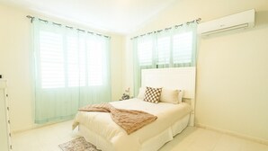 A bedroom with a bed, curtains, an air conditioner, and a rug.