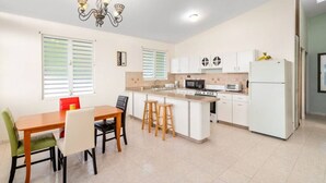 A modern kitchen with a dining area, featuring a central island, white cabinetry, and a chandelier.