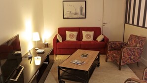 A living room with a red sofa, patterned armchair, and a coffee table. - Sauvageau - 1 chambre avec parking (Burdeos)