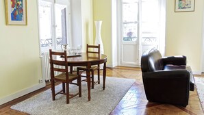 A dining area with a wooden table and chairs, a black leather sofa, and a white vase. - Louis Combes - Localisation Exceptionnelle / 1 cha (Burdeos)